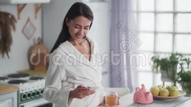 穿着白色浴袍的女人在手机上发信息，用手机在家工作